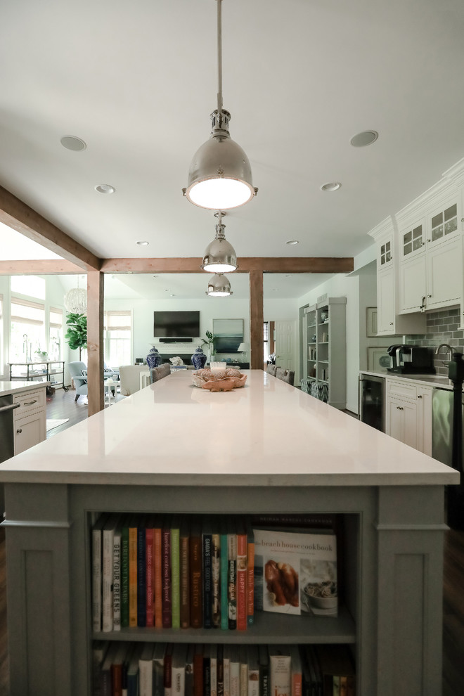 Foto di un cucina con isola centrale costiero con ante bianche, elettrodomestici in acciaio inossidabile, parquet scuro e pavimento marrone