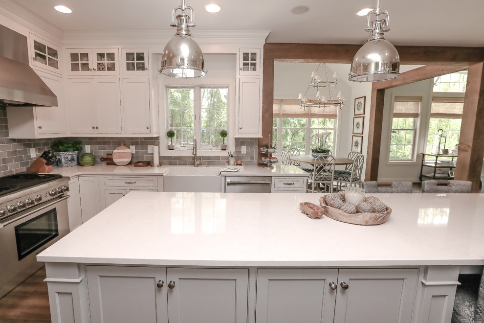 This is an example of a coastal kitchen in Other with white cabinets, stainless steel appliances, dark hardwood flooring, an island and brown floors.