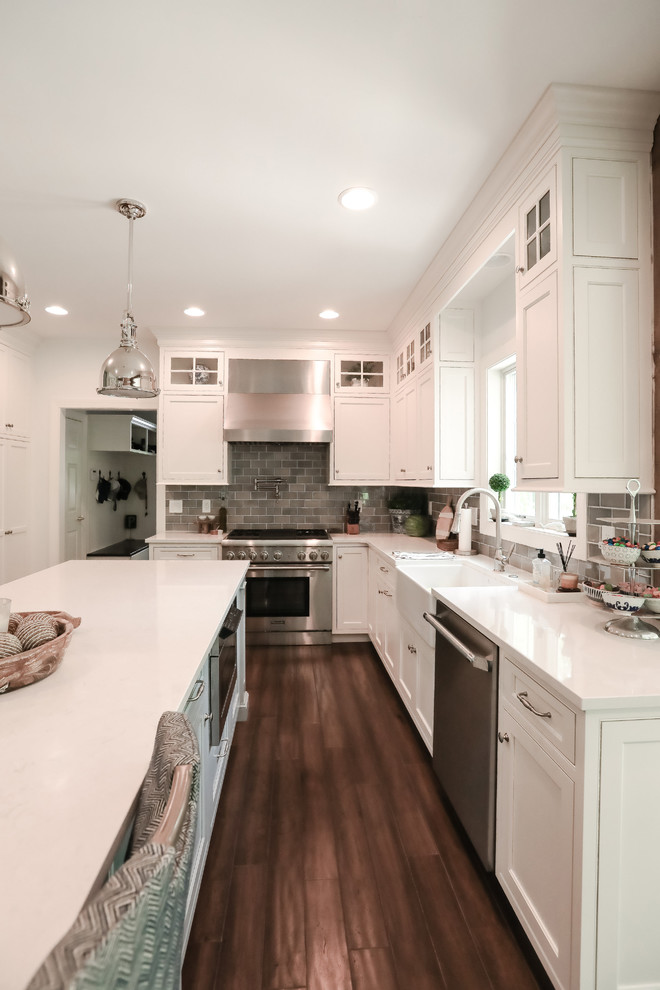 Immagine di un cucina con isola centrale costiero con ante bianche, elettrodomestici in acciaio inossidabile, parquet scuro e pavimento marrone