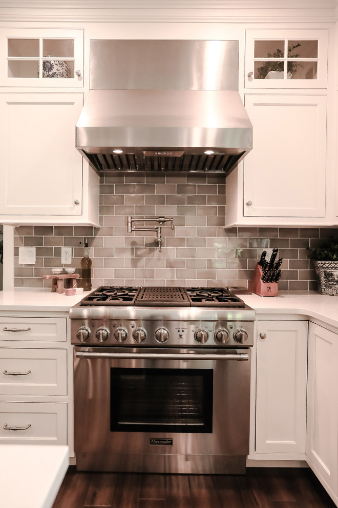 Esempio di un cucina con isola centrale stile marinaro con ante bianche, elettrodomestici in acciaio inossidabile, parquet scuro e pavimento marrone