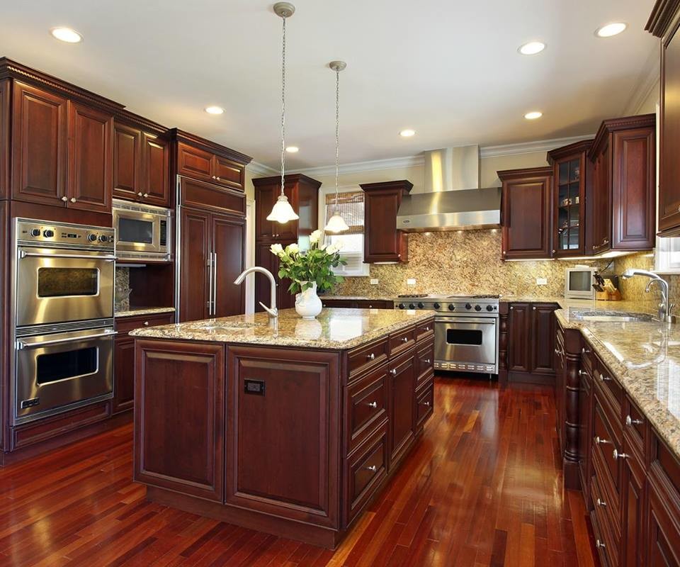 Inspiration for a mid-sized timeless u-shaped medium tone wood floor and brown floor eat-in kitchen remodel in Providence with a drop-in sink, raised-panel cabinets, beige cabinets, stainless steel countertops, beige backsplash, stone slab backsplash, stainless steel appliances and an island