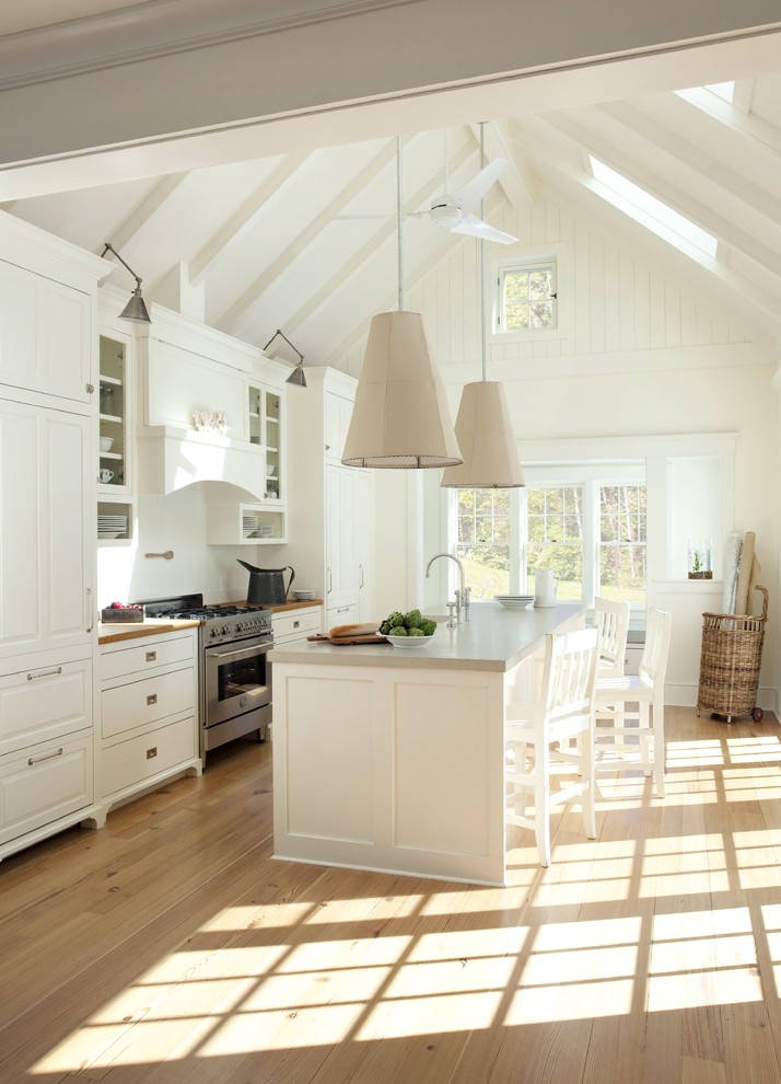 This is an example of a farmhouse galley kitchen in Boston with raised-panel cabinets, white cabinets, concrete worktops and integrated appliances.