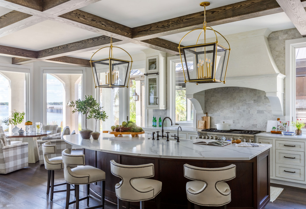 Photo of a large traditional l-shaped kitchen in Jacksonville with a double-bowl sink, beaded cabinets, white cabinets, engineered stone countertops, beige splashback, porcelain splashback, integrated appliances, dark hardwood flooring, an island, brown floors, white worktops and exposed beams.