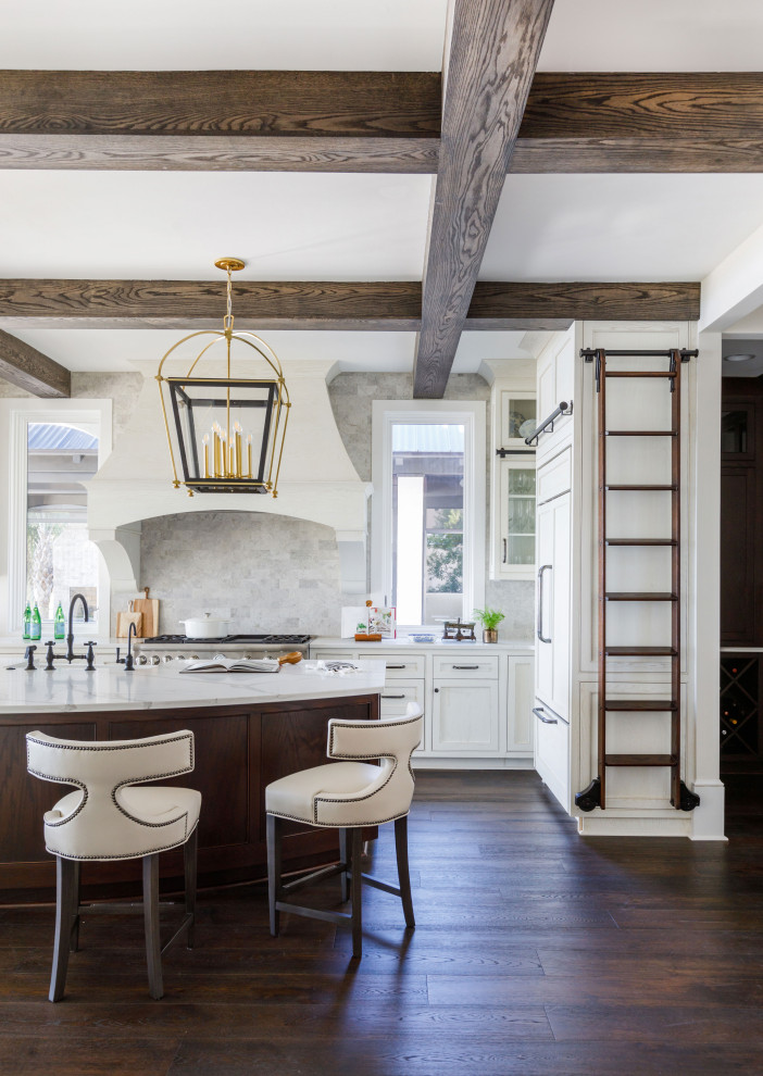 Inspiration for a large mediterranean l-shaped dark wood floor, brown floor and exposed beam kitchen remodel in Jacksonville with a double-bowl sink, beaded inset cabinets, white cabinets, quartz countertops, beige backsplash, porcelain backsplash, paneled appliances, an island and white countertops