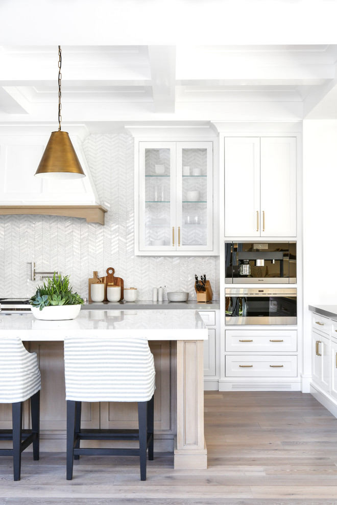 Foto di una grande cucina minimalista con ante bianche, top in superficie solida, paraspruzzi bianco, elettrodomestici in acciaio inossidabile, pavimento in legno massello medio, pavimento grigio e ante a filo