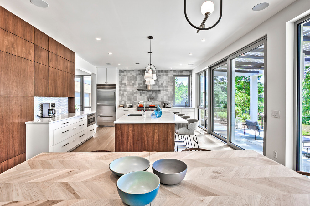 Mid-sized minimalist single-wall light wood floor and beige floor open concept kitchen photo in New York with an undermount sink, flat-panel cabinets, medium tone wood cabinets, quartz countertops, gray backsplash, cement tile backsplash, stainless steel appliances, an island and gray countertops