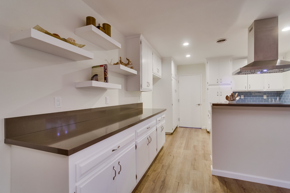 Maritime Wohnküche mit hellem Holzboden, weißen Schränken, Quarzwerkstein-Arbeitsplatte, Küchenrückwand in Blau, Rückwand aus Metrofliesen und Küchengeräten aus Edelstahl in Orange County