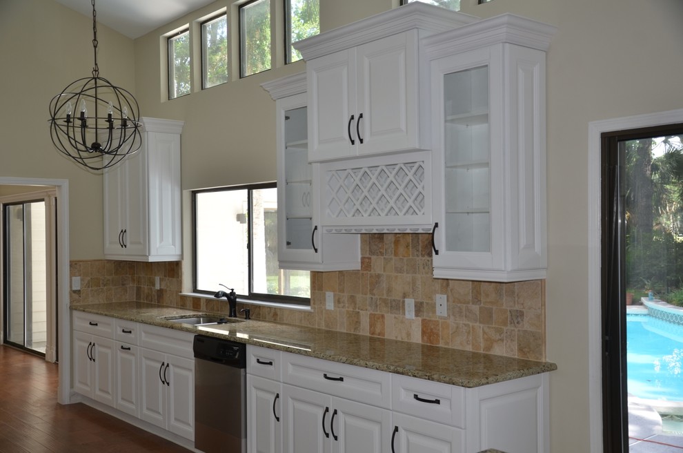 Exempel på ett stort klassiskt kök, med luckor med upphöjd panel, vita skåp, granitbänkskiva, brunt stänkskydd, stänkskydd i stenkakel, en dubbel diskho, rostfria vitvaror, mörkt trägolv och brunt golv