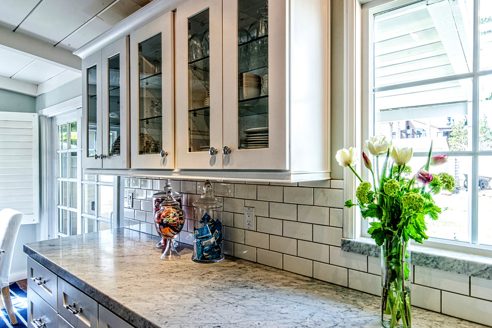 Photo of a medium sized traditional l-shaped open plan kitchen in San Diego with a submerged sink, shaker cabinets, white cabinets, granite worktops, white splashback, metro tiled splashback, stainless steel appliances, dark hardwood flooring, an island and brown floors.