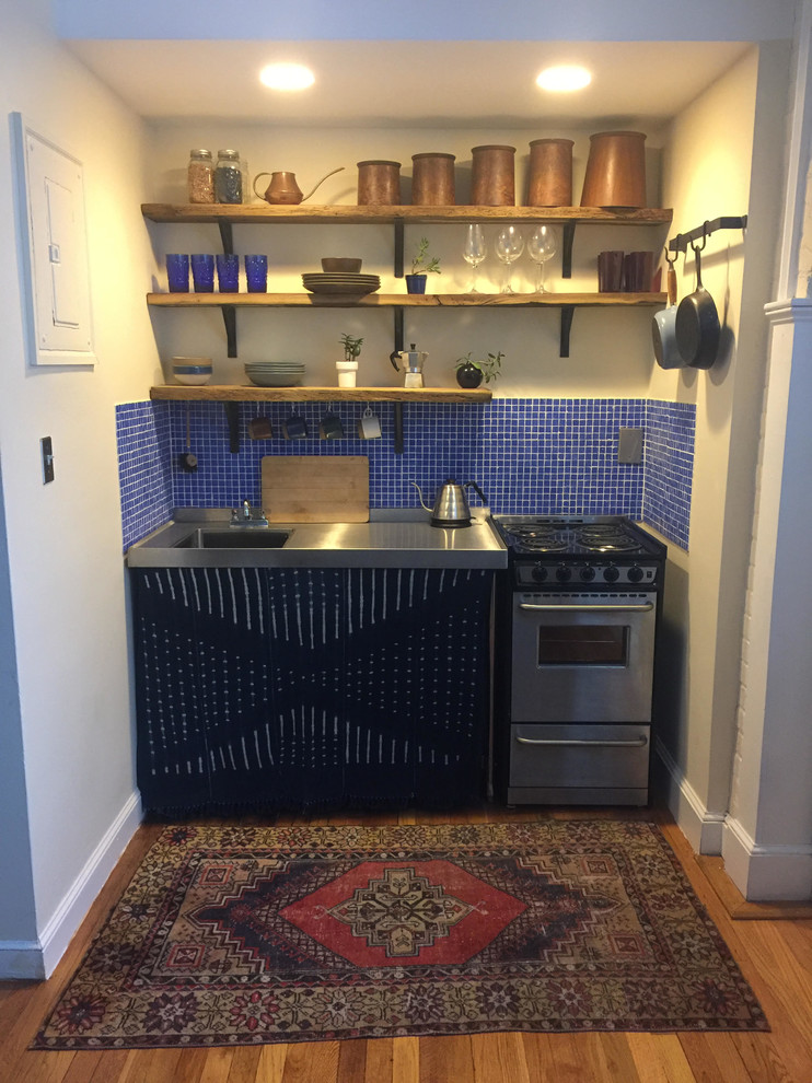 Example of a small mountain style single-wall medium tone wood floor enclosed kitchen design in Boston with stainless steel countertops, blue backsplash, glass tile backsplash, stainless steel appliances and no island