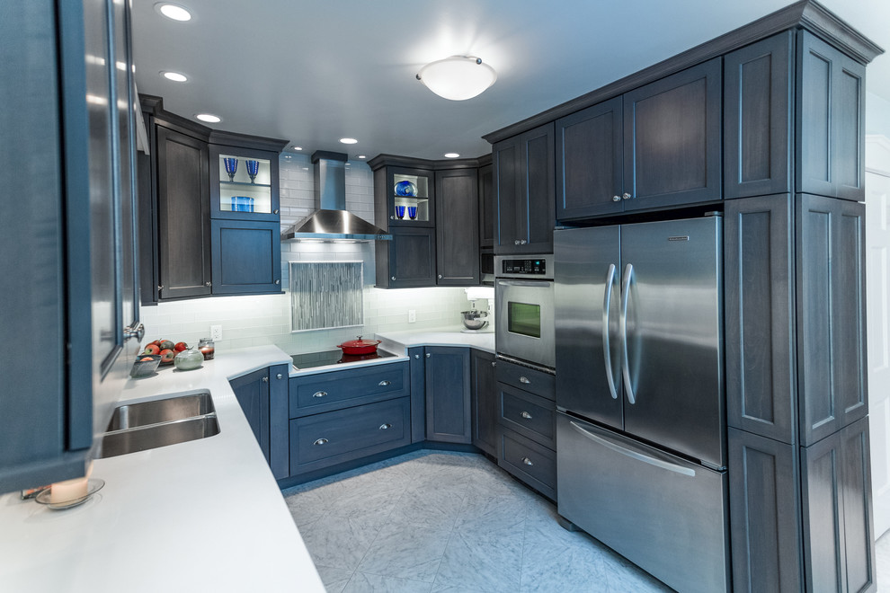 Exemple d'une petite cuisine américaine chic en U avec un placard à porte shaker, des portes de placard bleues, un plan de travail en quartz modifié, une crédence blanche et un électroménager en acier inoxydable.