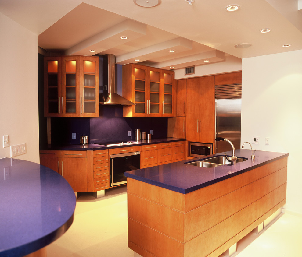 Cette image montre une petite cuisine américaine minimaliste en U et bois brun avec un évier encastré, un placard à porte plane, un plan de travail en terrazzo, une crédence bleue, un électroménager en acier inoxydable, un sol en calcaire, 2 îlots et un plan de travail bleu.