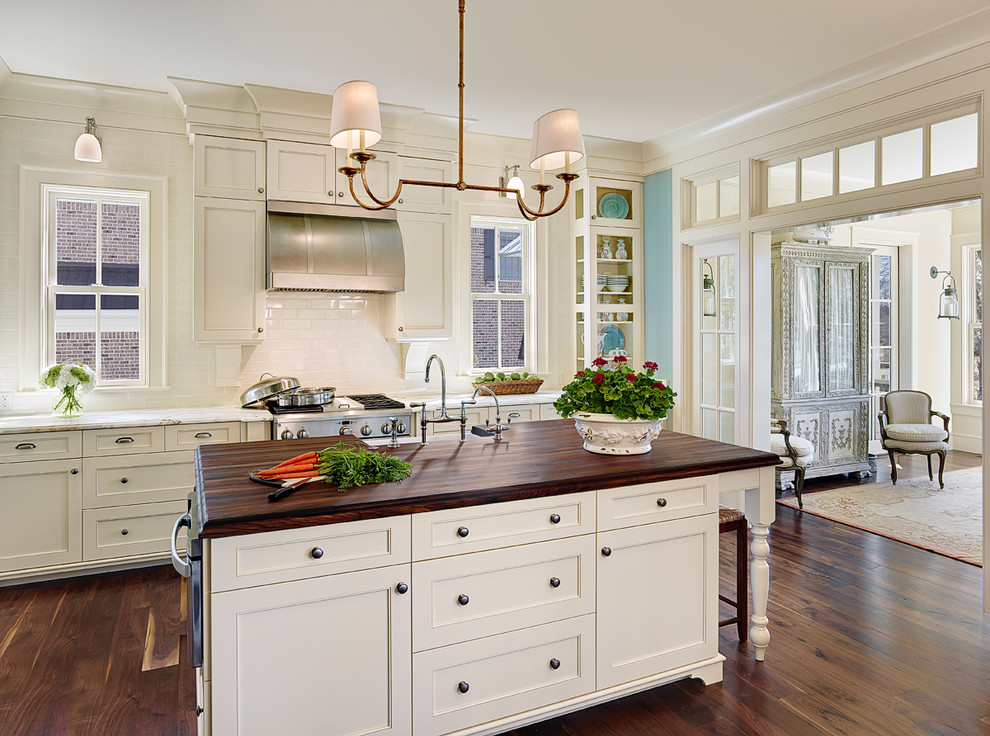 Klassische Küche mit weißen Schränken, Arbeitsplatte aus Holz, Küchenrückwand in Weiß, Rückwand aus Metrofliesen und Schrankfronten mit vertiefter Füllung in Charleston
