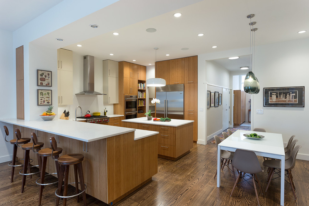 Example of a mid-sized trendy l-shaped medium tone wood floor eat-in kitchen design in New York with an undermount sink, flat-panel cabinets, medium tone wood cabinets, quartz countertops, white backsplash, stainless steel appliances and an island