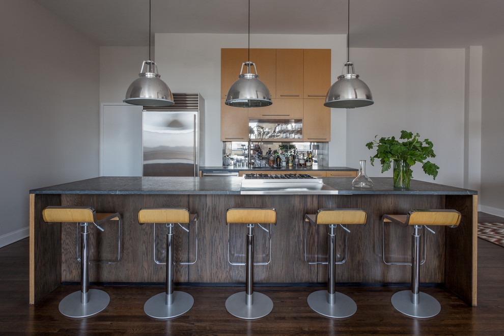 Inspiration for a large industrial single-wall dark wood floor eat-in kitchen remodel in New York with a single-bowl sink, flat-panel cabinets, light wood cabinets, granite countertops, gray backsplash, glass tile backsplash, stainless steel appliances and an island