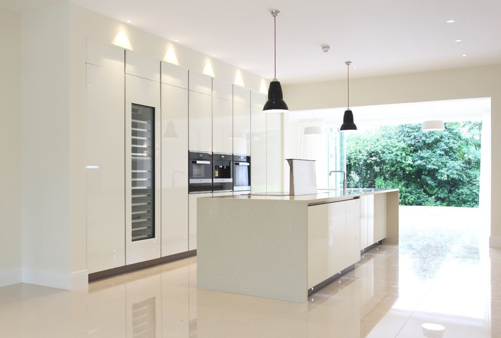 Eat-in kitchen - large contemporary single-wall porcelain tile eat-in kitchen idea in Kent with a single-bowl sink, flat-panel cabinets, white cabinets, solid surface countertops, beige backsplash, black appliances and an island