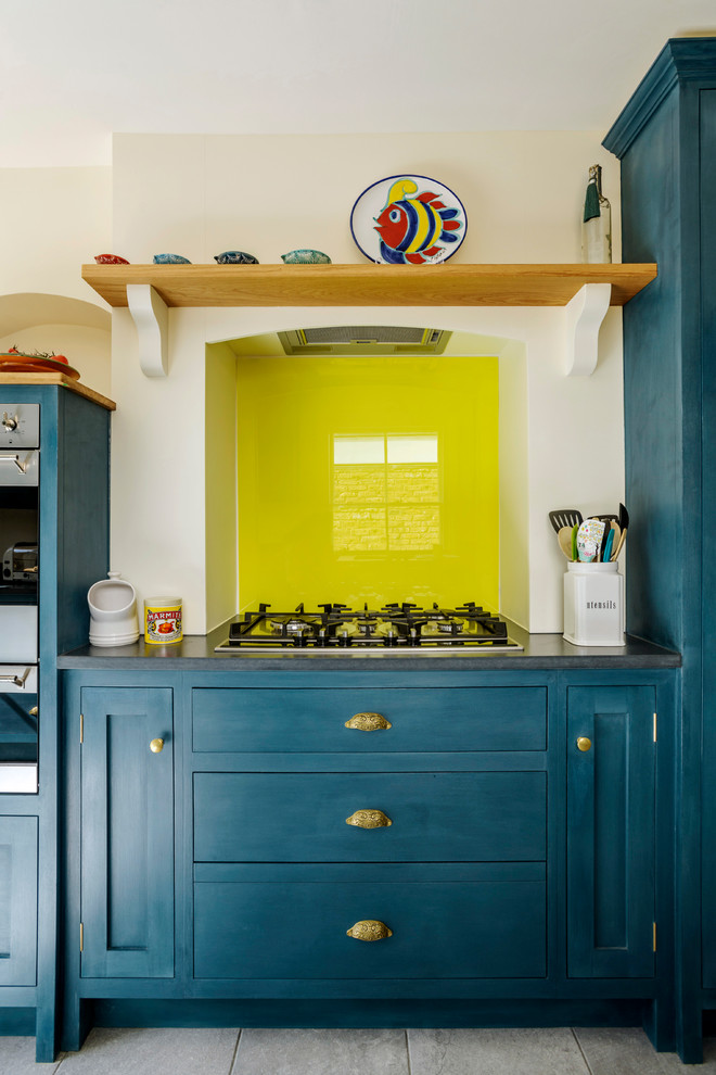 Esempio di una cucina chic con lavello stile country, ante in stile shaker, ante blu, top in granito, paraspruzzi giallo, paraspruzzi con lastra di vetro, pavimento con piastrelle in ceramica e top nero