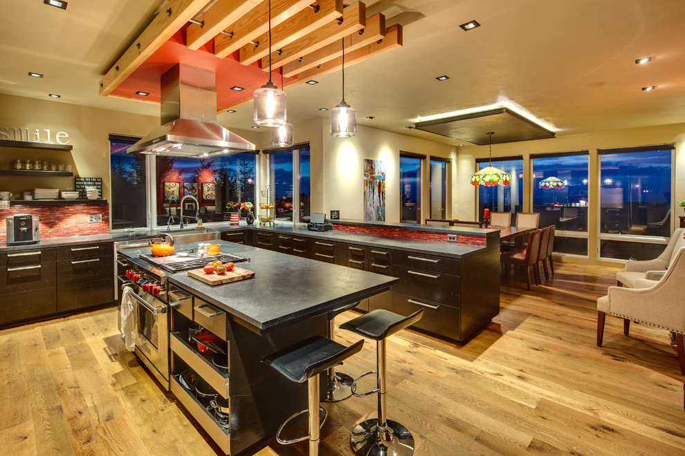 Example of a large transitional u-shaped light wood floor eat-in kitchen design in Other with a farmhouse sink, flat-panel cabinets, dark wood cabinets, concrete countertops, red backsplash, glass tile backsplash, stainless steel appliances and an island