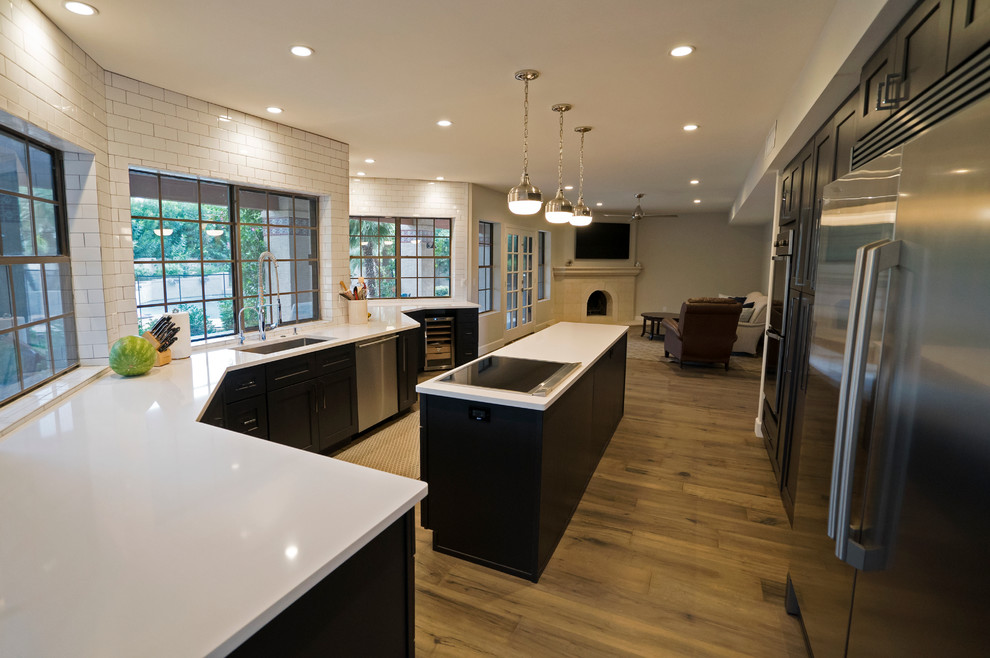 Inspiration for a transitional light wood floor kitchen remodel in Other with a single-bowl sink, shaker cabinets, black cabinets, quartz countertops, white backsplash, subway tile backsplash, stainless steel appliances and an island