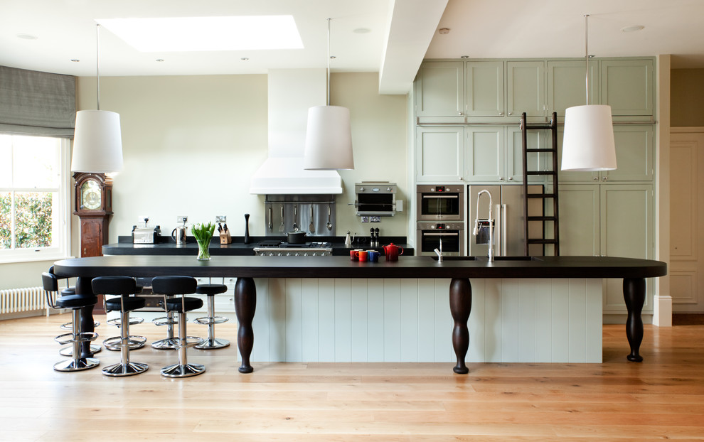 Photo of an expansive victorian galley kitchen in London with shaker cabinets, grey cabinets, stainless steel appliances, medium hardwood flooring and an island.