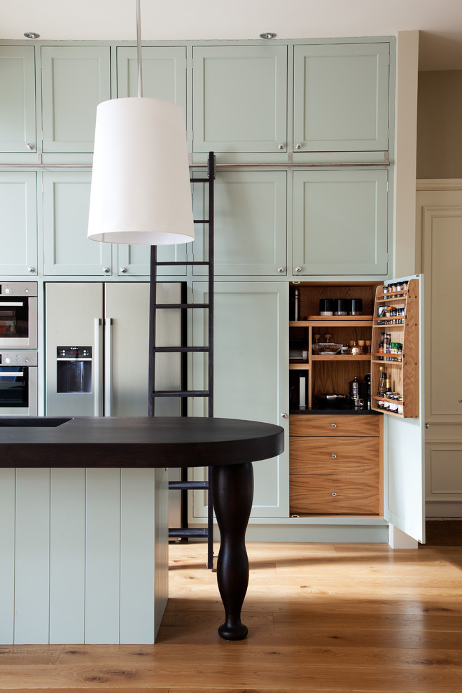 Zweizeilige Klassische Küche mit integriertem Waschbecken, Schrankfronten im Shaker-Stil, Küchengeräten aus Edelstahl, braunem Holzboden, Kücheninsel und blauen Schränken in London