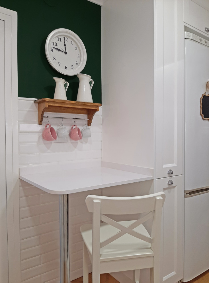 Immagine di una cucina a L country chiusa e di medie dimensioni con lavello a doppia vasca, ante a filo, pavimento in laminato, penisola e top bianco