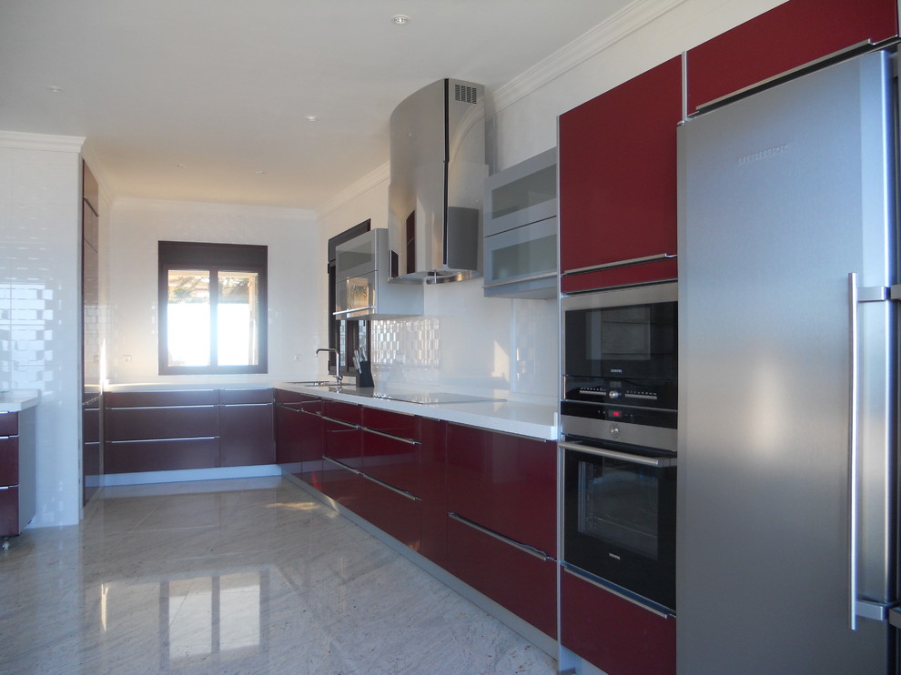 Cette photo montre une grande cuisine ouverte tendance en L avec un placard à porte plane, des portes de placard rouges, une crédence blanche, un électroménager en acier inoxydable et aucun îlot.