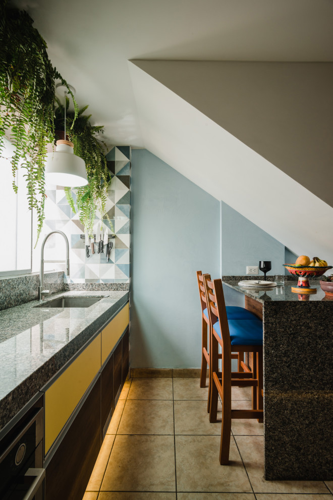 Einzeilige Moderne Küche mit Unterbauwaschbecken, flächenbündigen Schrankfronten, gelben Schränken, Halbinsel, beigem Boden und grauer Arbeitsplatte in Sonstige