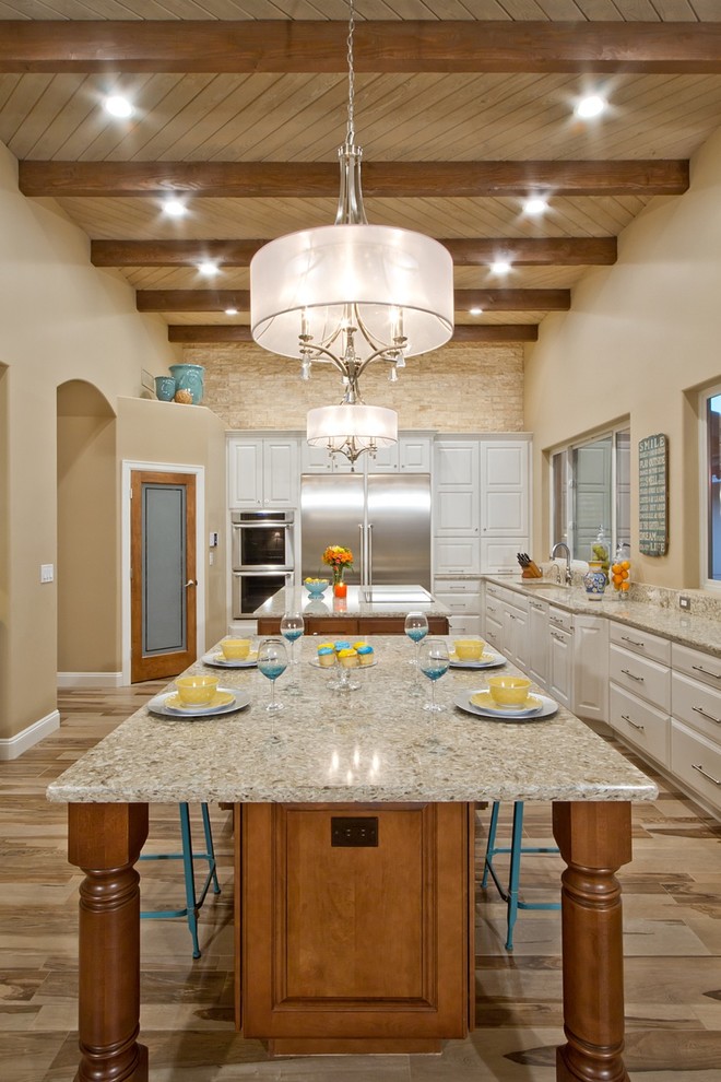 Inspiration for a large contemporary galley kitchen/diner in Phoenix with a built-in sink, beaded cabinets, white cabinets, granite worktops, beige splashback, stainless steel appliances, light hardwood flooring, multiple islands and brown floors.