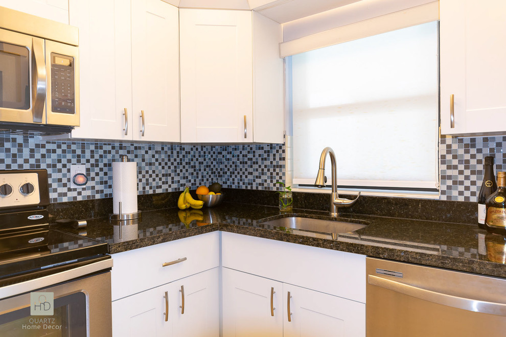 Example of a small danish l-shaped cement tile floor and white floor enclosed kitchen design in Miami with a single-bowl sink, white cabinets, granite countertops, blue backsplash, glass tile backsplash, stainless steel appliances, no island and black countertops