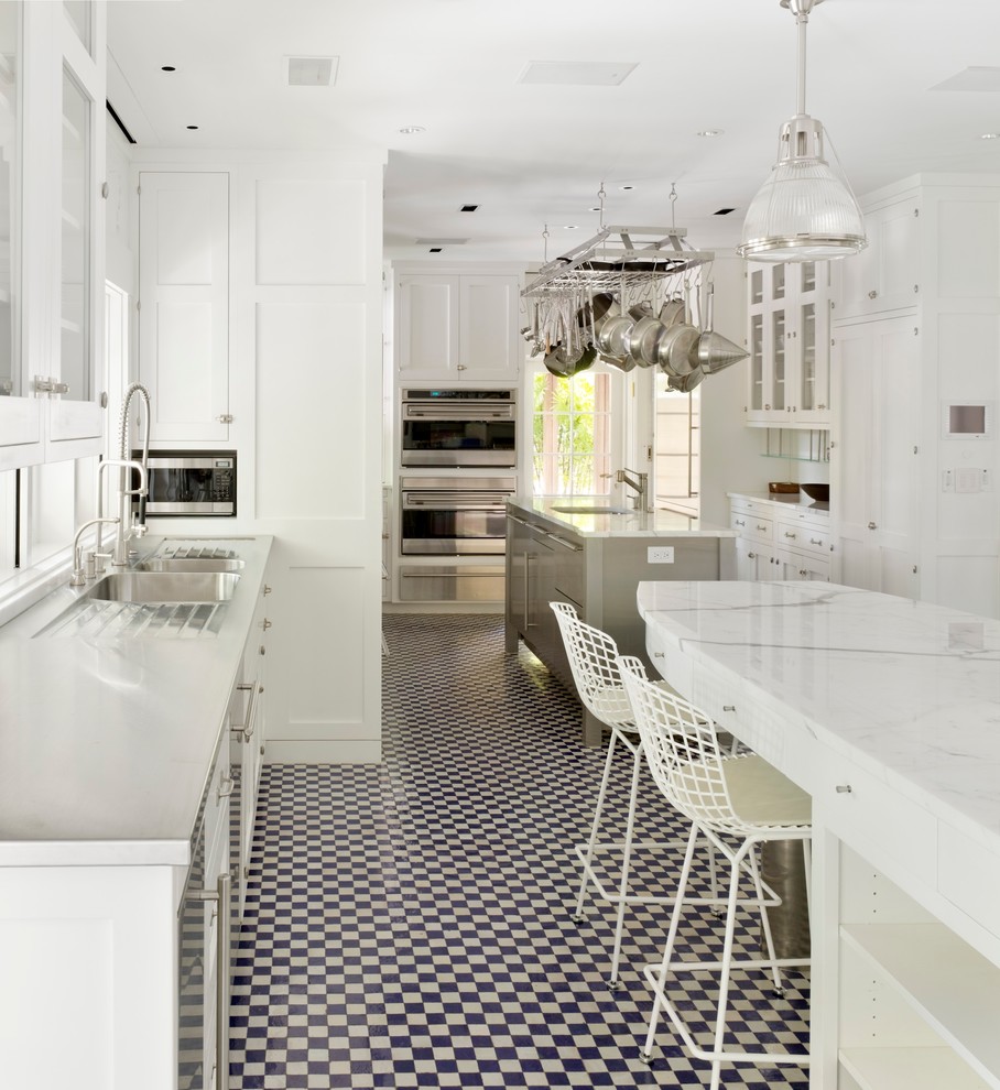 Bild på ett stort, avskilt funkis u-kök, med en dubbel diskho, skåp i shakerstil, vita skåp, rostfria vitvaror, flera köksöar, marmorbänkskiva, vitt stänkskydd, stänkskydd i glaskakel och klinkergolv i porslin