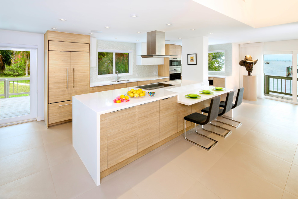 Inspiration for a large modern galley kitchen in Miami with a submerged sink, flat-panel cabinets, light wood cabinets, engineered stone countertops, white splashback, mosaic tiled splashback, integrated appliances and porcelain flooring.