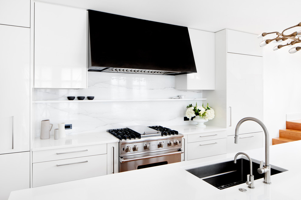 Cette image montre une cuisine minimaliste avec un évier encastré, un placard à porte plane, un plan de travail en quartz modifié, une crédence blanche, un électroménager en acier inoxydable, îlot et une crédence en marbre.