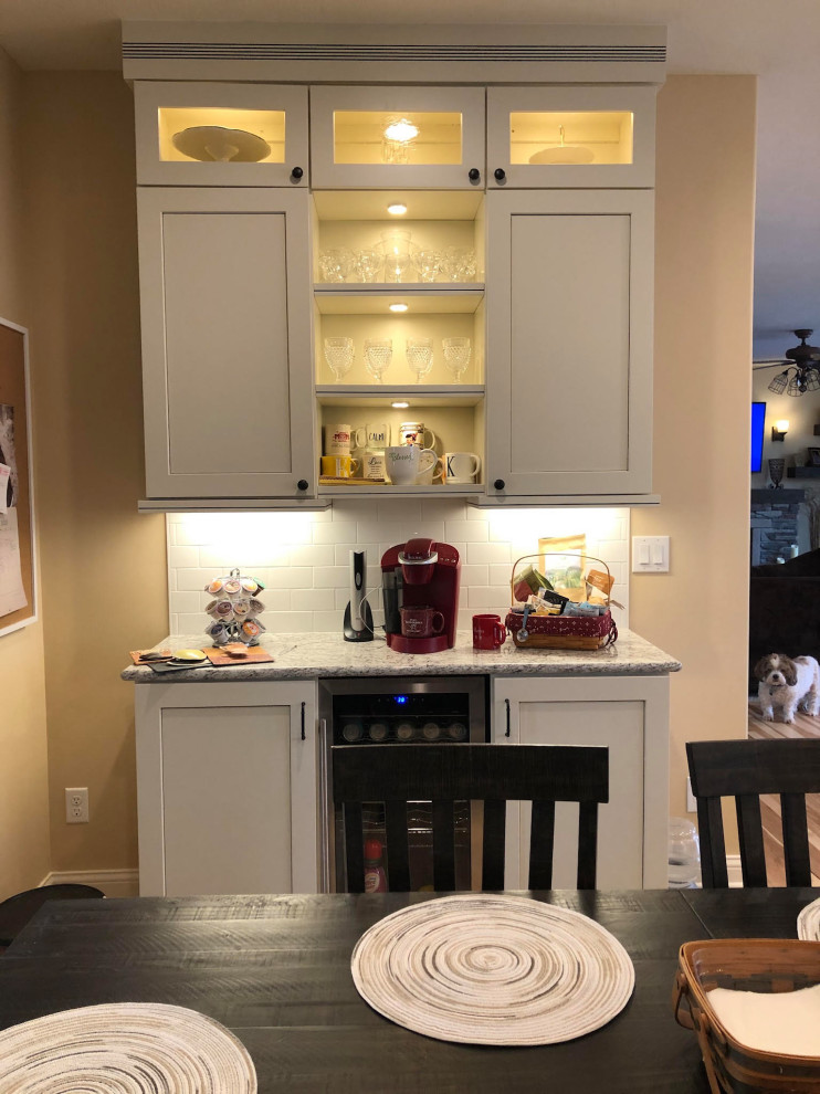 Foto på ett stort lantligt flerfärgad kök, med en undermonterad diskho, luckor med infälld panel, vita skåp, granitbänkskiva, grått stänkskydd, stänkskydd i trä, rostfria vitvaror, ljust trägolv, en köksö och brunt golv