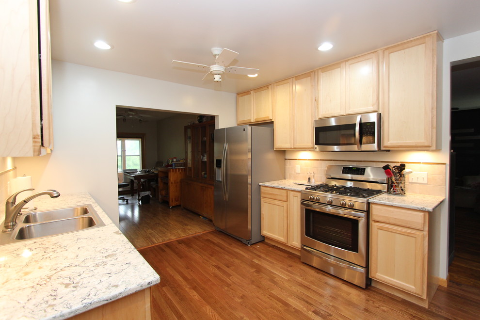 Medium sized traditional galley enclosed kitchen in Grand Rapids with a built-in sink, recessed-panel cabinets, medium wood cabinets, engineered stone countertops, beige splashback, ceramic splashback, stainless steel appliances, light hardwood flooring and no island.