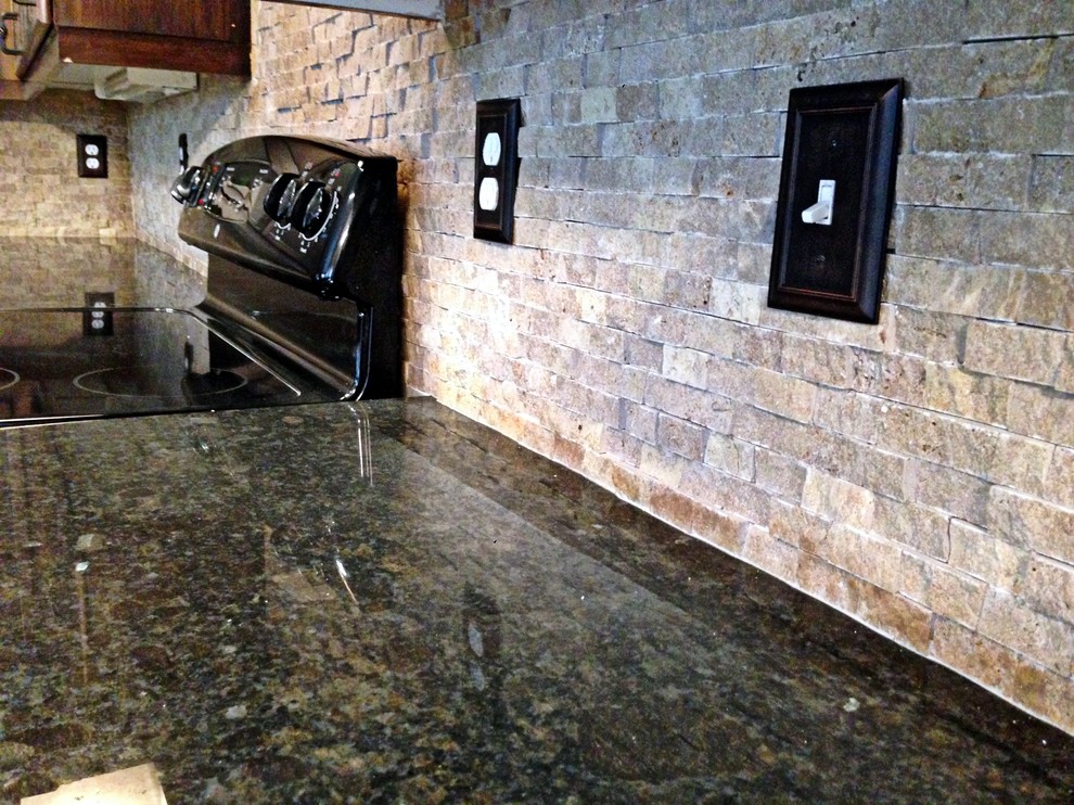 Réalisation d'une cuisine ouverte design en bois foncé de taille moyenne avec un évier 2 bacs, un placard avec porte à panneau encastré, un plan de travail en granite, une crédence grise, une crédence en carrelage de pierre, parquet clair et îlot.