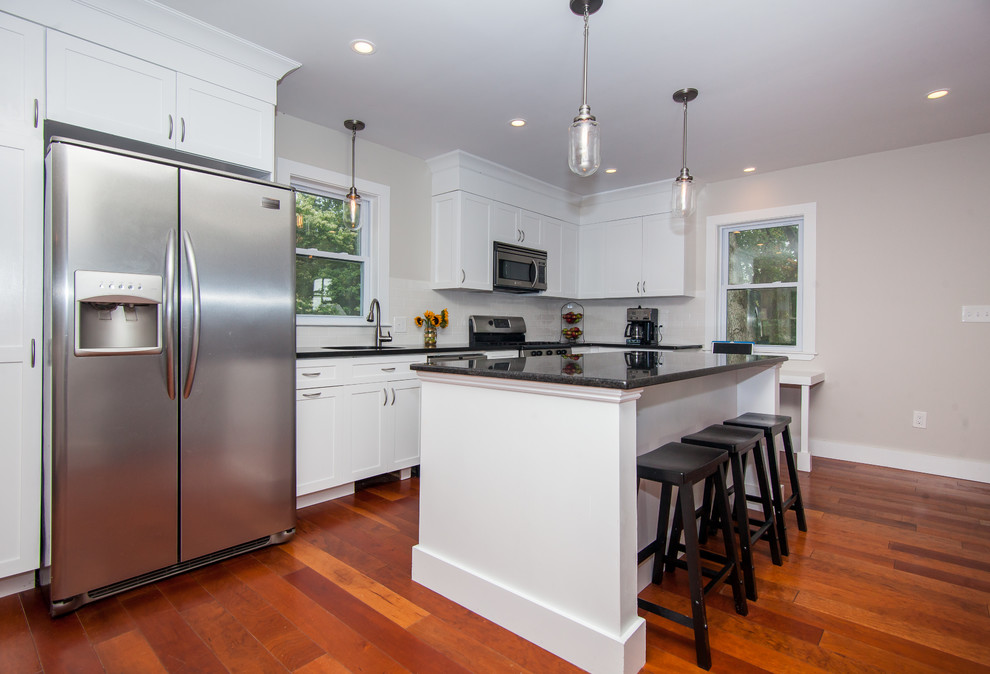 Inspiration for a mid-sized farmhouse l-shaped dark wood floor eat-in kitchen remodel in Boston with an undermount sink, shaker cabinets, white cabinets, wood countertops, white backsplash, subway tile backsplash, stainless steel appliances and an island