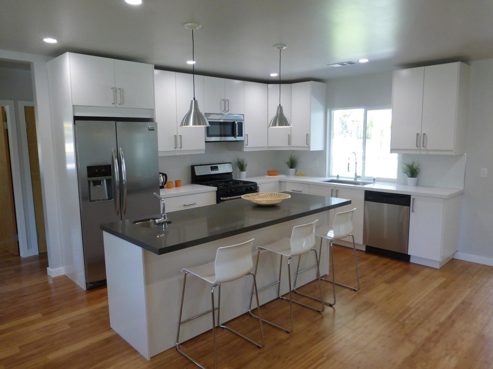 Example of a mid-century modern l-shaped light wood floor eat-in kitchen design in Los Angeles with flat-panel cabinets, white cabinets, quartz countertops, stainless steel appliances and an island