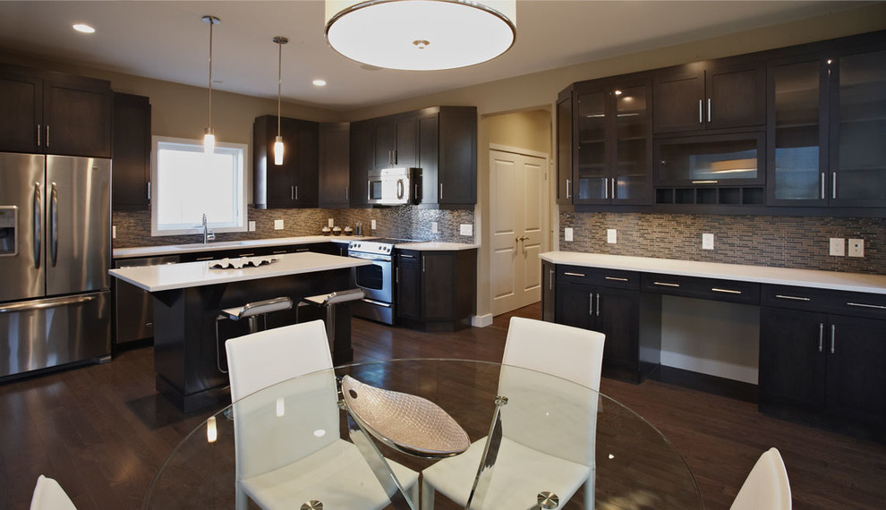 This is an example of a large contemporary l-shaped kitchen/diner in Other with a double-bowl sink, glass-front cabinets, dark wood cabinets, engineered stone countertops, brown splashback, stainless steel appliances, laminate floors and an island.