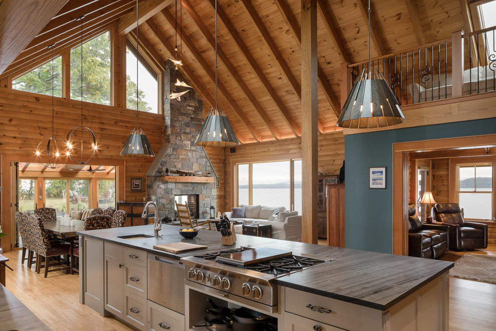Exempel på ett rustikt kök med öppen planlösning, med luckor med infälld panel, gröna skåp, bänkskiva i täljsten, rostfria vitvaror, ljust trägolv och en köksö