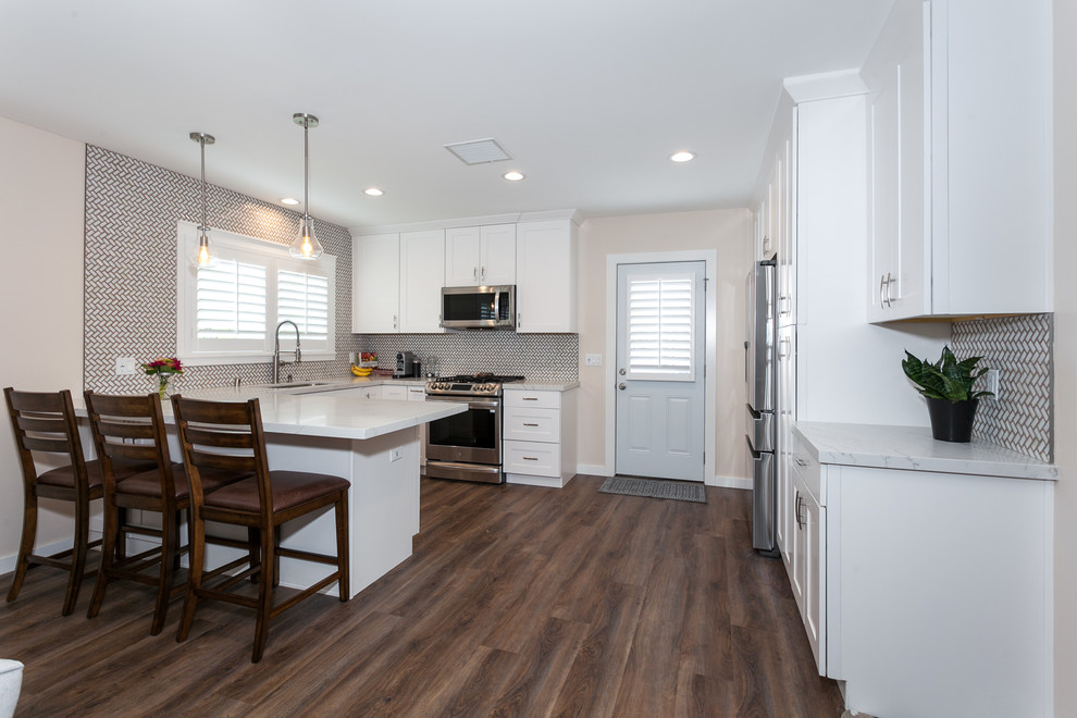 Example of a mid-sized minimalist u-shaped vinyl floor and brown floor eat-in kitchen design in Los Angeles with a double-bowl sink, beaded inset cabinets, white cabinets, quartz countertops, multicolored backsplash, subway tile backsplash, stainless steel appliances, a peninsula and white countertops