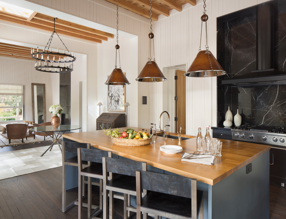 Idee per un cucina con isola centrale country con lavello sottopiano, ante lisce, ante nere, top in legno, paraspruzzi nero e parquet scuro