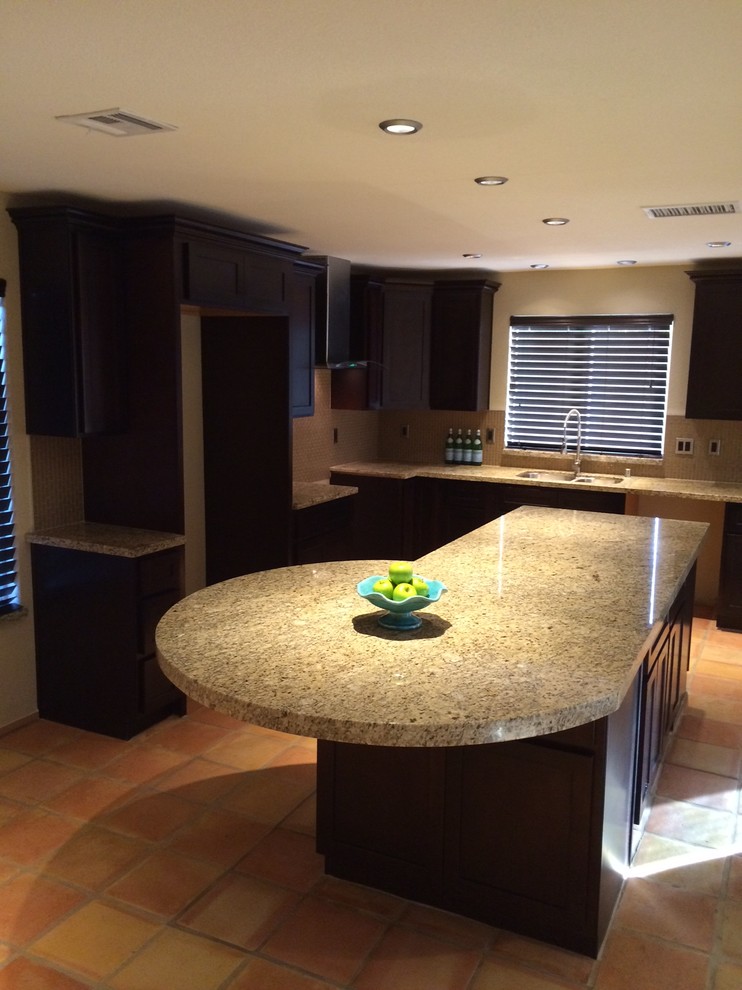 Photo of a small contemporary u-shaped kitchen/diner in Las Vegas with an island, shaker cabinets, dark wood cabinets, granite worktops, beige splashback, glass tiled splashback, stainless steel appliances, a submerged sink and terracotta flooring.