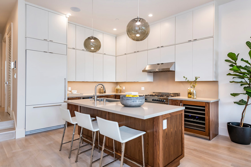 Inspiration for a medium sized modern l-shaped kitchen/diner in San Francisco with a single-bowl sink, flat-panel cabinets, white cabinets, engineered stone countertops, white splashback, porcelain splashback, stainless steel appliances, light hardwood flooring, an island, beige floors and white worktops.