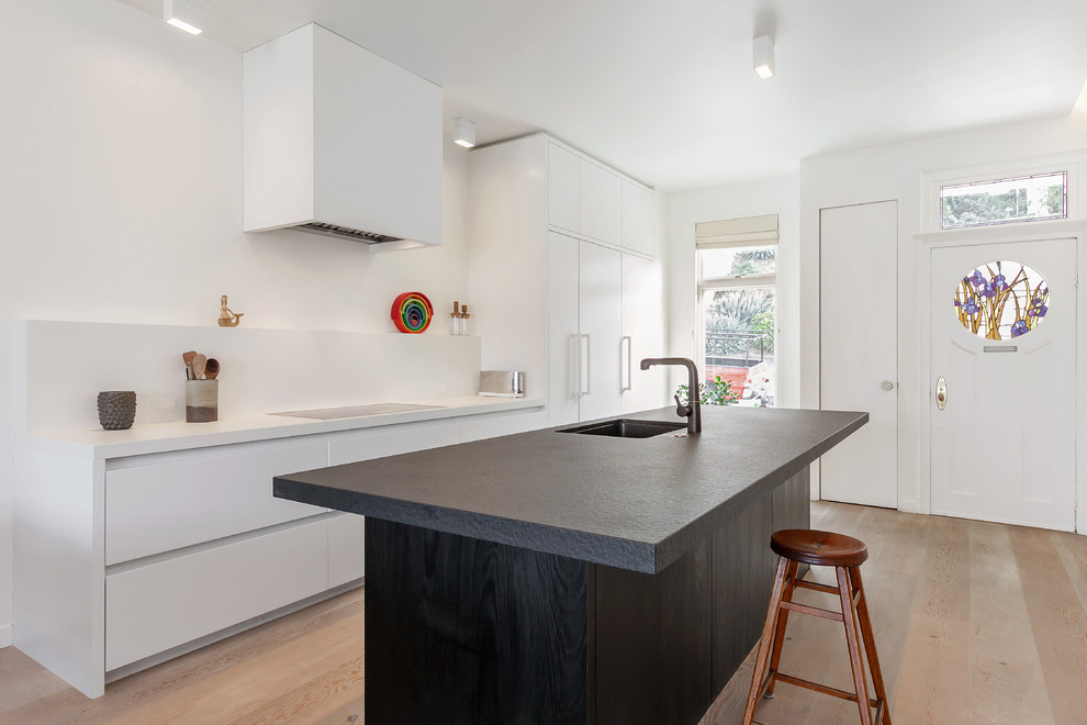 Zweizeilige, Große Nordische Küche mit integriertem Waschbecken, flächenbündigen Schrankfronten, Granit-Arbeitsplatte, weißen Elektrogeräten, hellem Holzboden und Kücheninsel in San Francisco