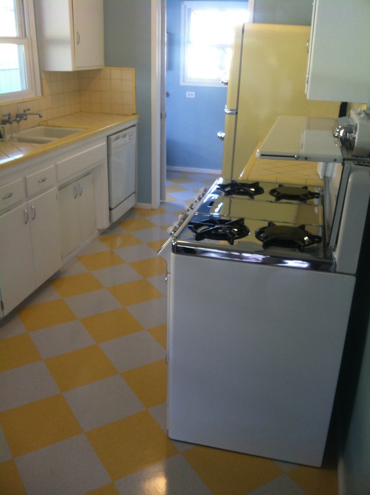 Example of a small arts and crafts single-wall vinyl floor enclosed kitchen design in San Diego with a drop-in sink, flat-panel cabinets, white cabinets, tile countertops, yellow backsplash, ceramic backsplash, colored appliances and no island