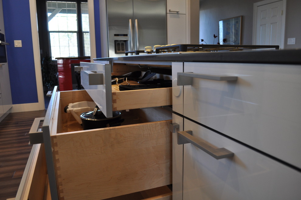 Modern inredning av ett mellanstort kök, med en undermonterad diskho, släta luckor, vita skåp, bänkskiva i kvarts, vitt stänkskydd, stänkskydd i sten, rostfria vitvaror, mellanmörkt trägolv och en köksö