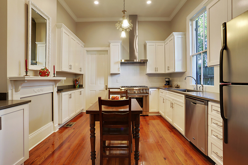 Medium sized classic u-shaped enclosed kitchen in New Orleans with a submerged sink, shaker cabinets, white cabinets, engineered stone countertops, stainless steel appliances, medium hardwood flooring, no island, brown floors and grey worktops.