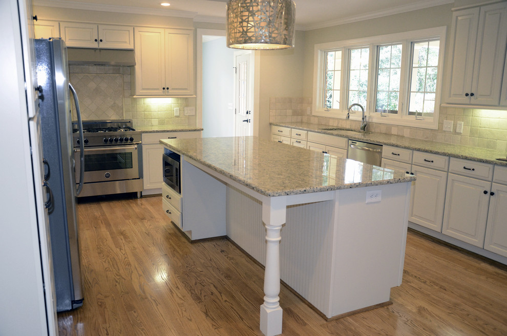 Eat-in kitchen - traditional u-shaped eat-in kitchen idea in Other with an undermount sink, raised-panel cabinets, white cabinets, granite countertops, beige backsplash, porcelain backsplash and stainless steel appliances