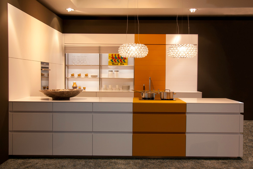 Cette photo montre une petite cuisine parallèle tendance avec un placard à porte plane, un plan de travail en surface solide, un électroménager en acier inoxydable, moquette et une péninsule.
